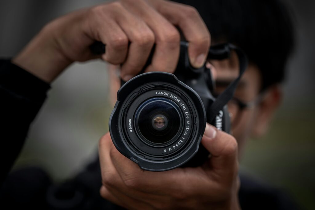 Focused shot of a photographer gripping a camera lens, creating a dynamic portrait.